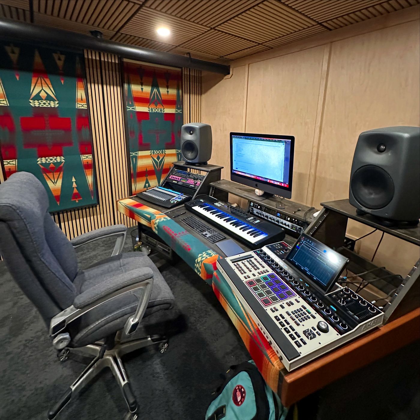The mix position from the engineer's chair: a keyboard controller, a drum-pad sampler with a touchscreen, a digital mixer and the main computer between two studio monitors.